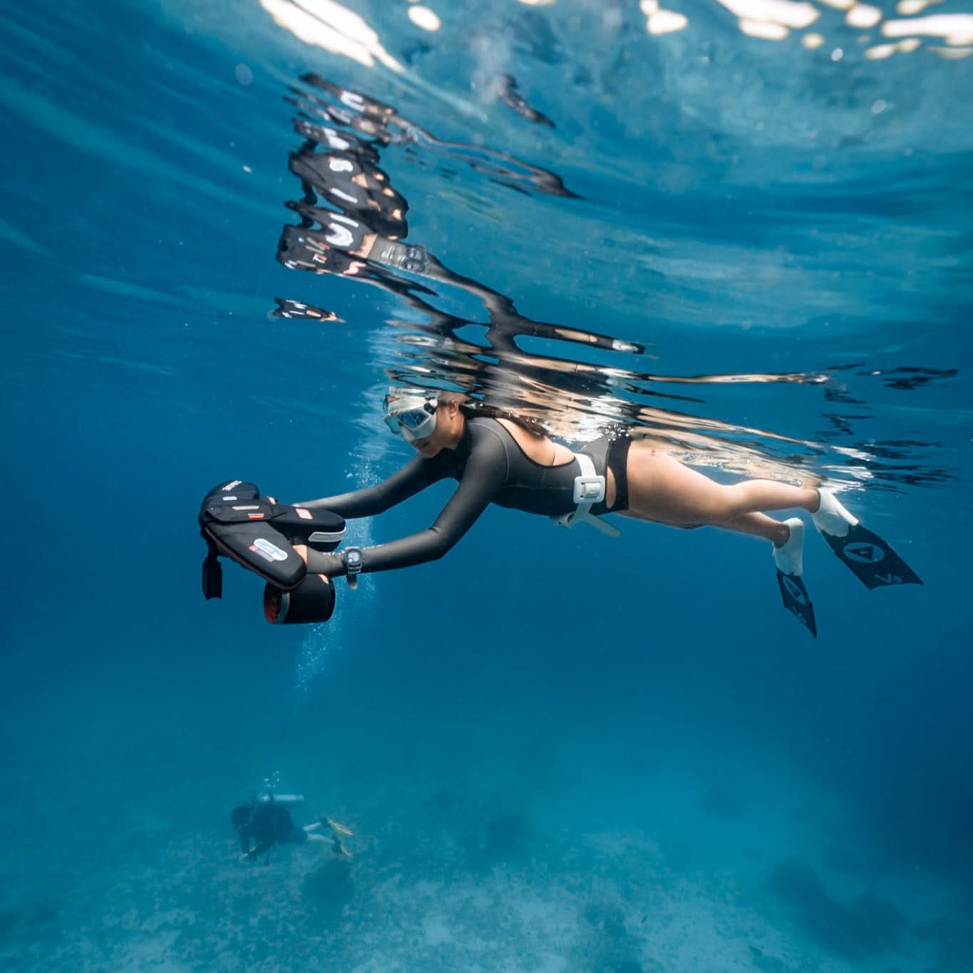 Diver maneuvering a Sublue Navbow underwater scooter in clear ocean water. Image via Sublue.